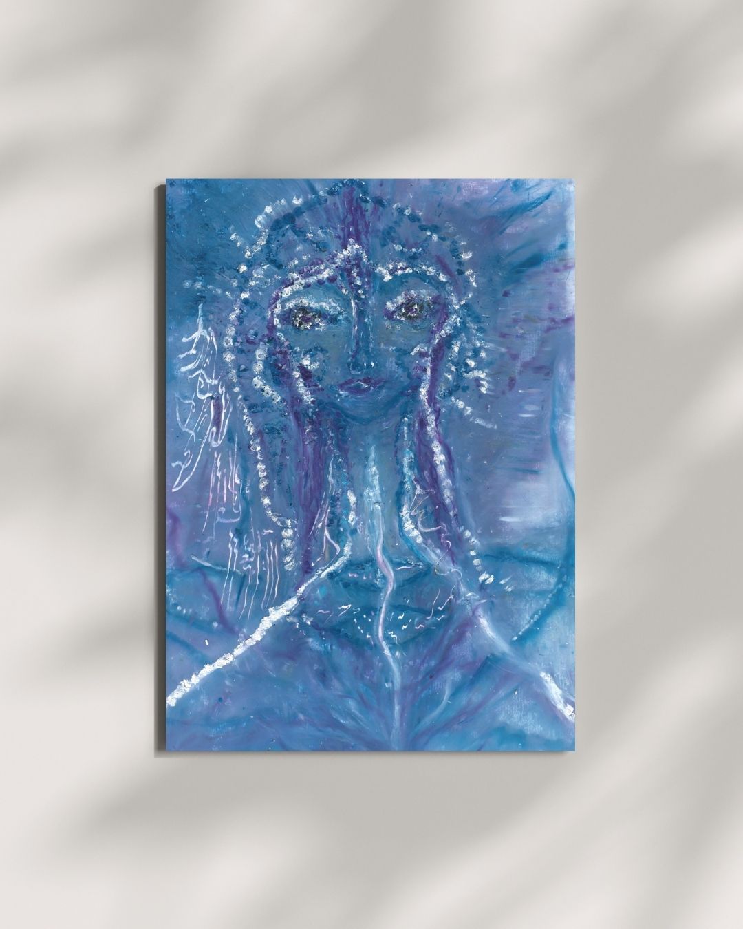 A4 oil pastel drawing titled Priestess of the Blue Lotus, featuring a mystical feminine figure in deep blue and purple tones. Her face is adorned with shimmering white and silver accents, and her presence radiates a serene, otherworldly energy. The background flows with abstract blue hues, evoking the essence of the blue lotus.