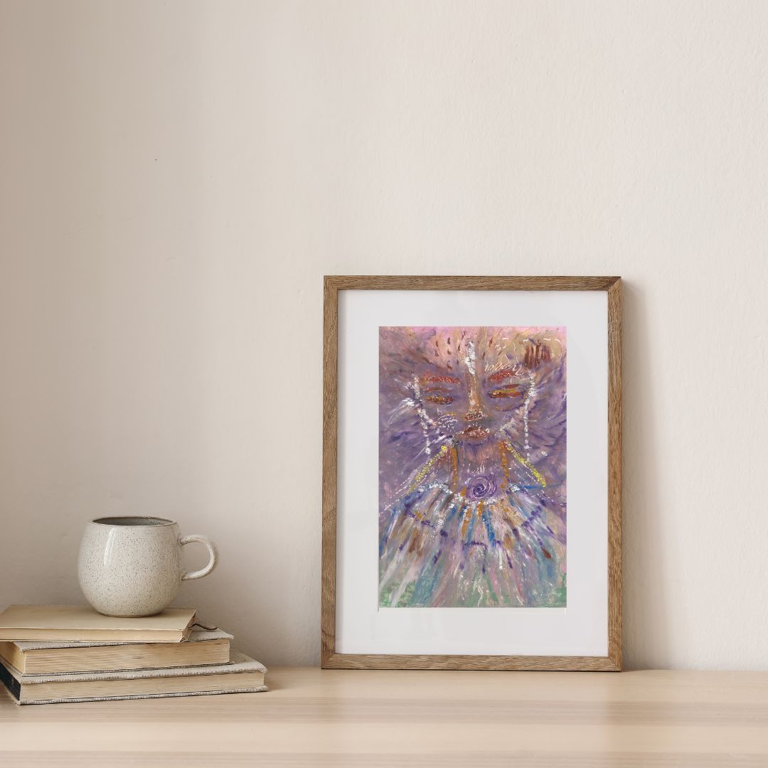 Ajuji, a whimsical Lyran star being with cat-like features, framed in a wooden frame with a white passe-partout, placed on a desk next to a stack of books and a coffee cup.